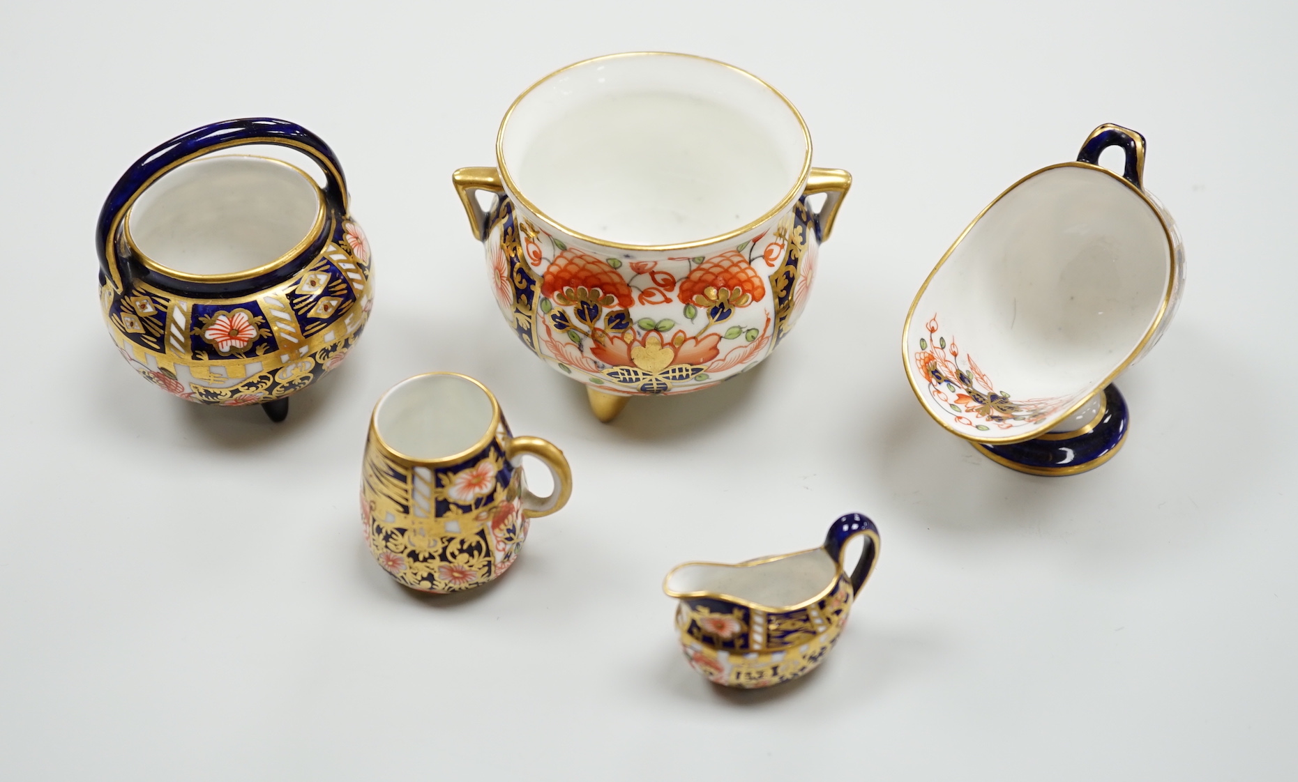 20th century Derby miniature wares in Imari patterns including a mug, a sauceboat, a cauldron, a large cauldron and a spoon warmer